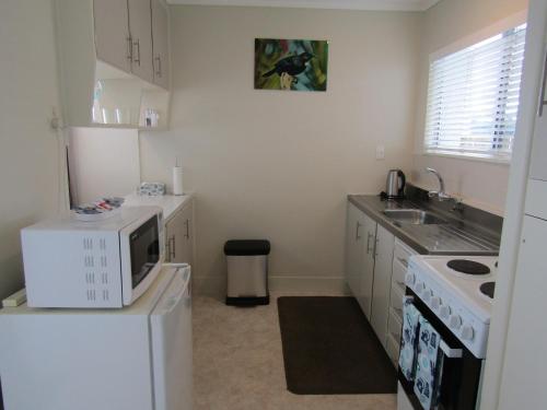 a kitchen with a microwave on top of a refrigerator at Anchorage Motel in Whitianga