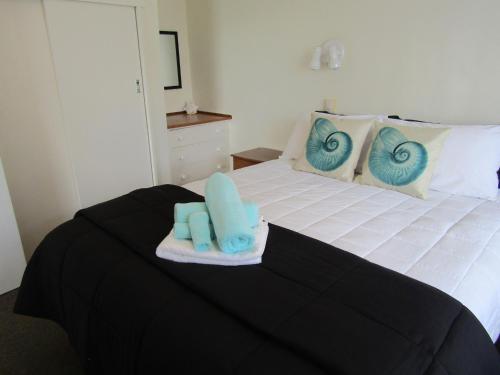 a bedroom with a bed with blue towels on it at Anchorage Motel in Whitianga