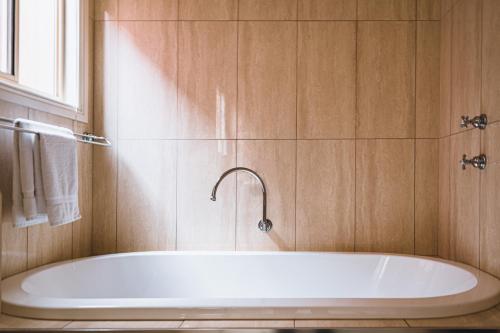 a white tub in a bathroom with a window at Wattle Terrace in Castlemaine