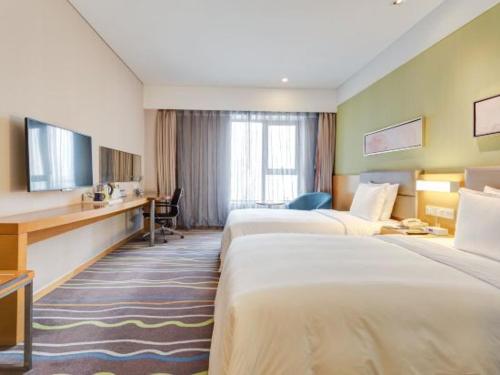 a hotel room with two beds and a desk at Holiday Inn Express Xi'an High-Tech Zone, an IHG Hotel in Xi'an