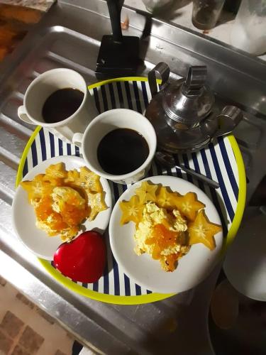 a table with two plates of food and cups of coffee at Tarragona Hostal in Santa Rosa de Cabal