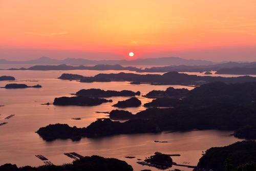 a sunset over a body of water with rocks at Tabist Sasebo Palace Hotel in Sasebo