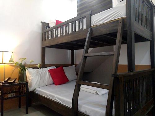 a bunk bed with a ladder and a couch in a room at Jil's Apartelle in Tagaytay