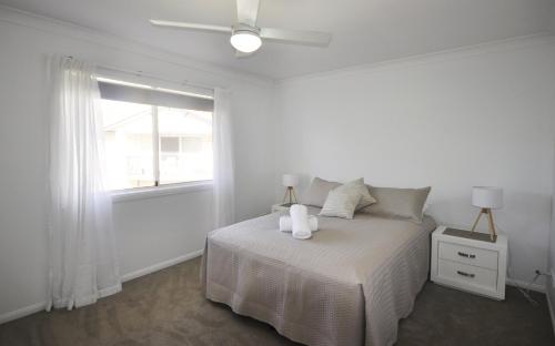 a white bedroom with a bed and a window at Bellissimo - 2 Bedroom apartment in the Sylvan Beach Resort! in Bellara