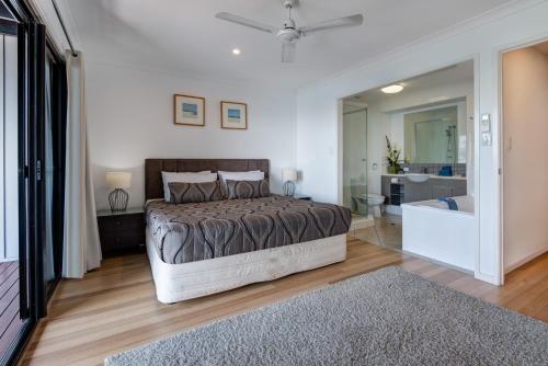 a bedroom with a bed and a bathroom with a tub at Sea View Shorelines Hamilton Island in Hamilton Island