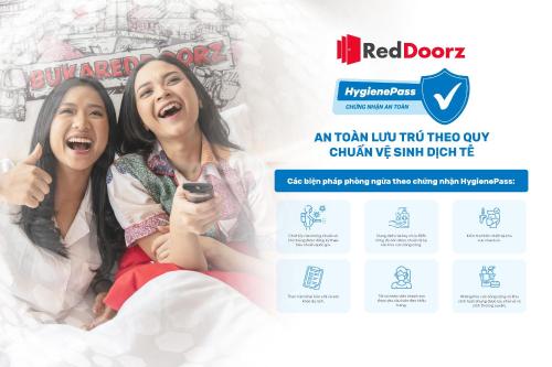 two girls sitting on a bed with a redbook website at RedDoorz Hon En Hotel Le Loi Go Vap in Ho Chi Minh City