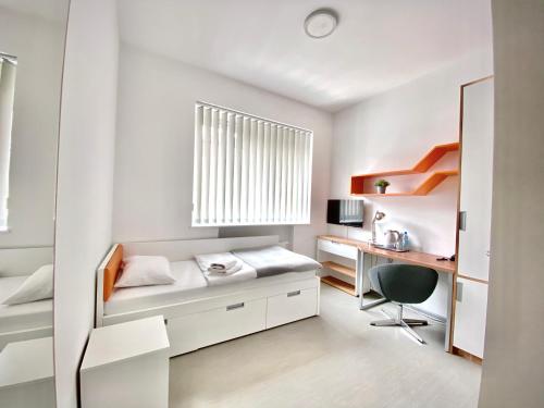 a white bedroom with a desk and a bed at Esperanto Home in Katowice