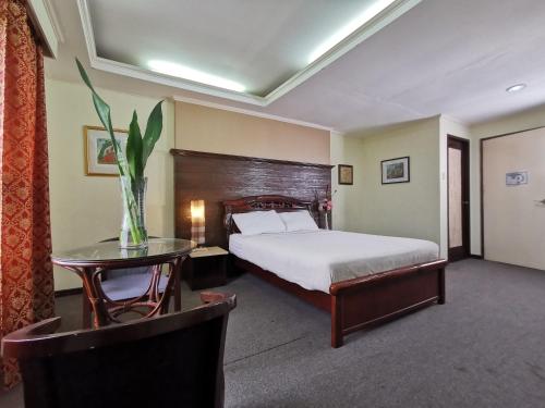 Un dormitorio con una cama y una mesa con un jarrón. en Cebu Hilltop Hotel, en Cebú