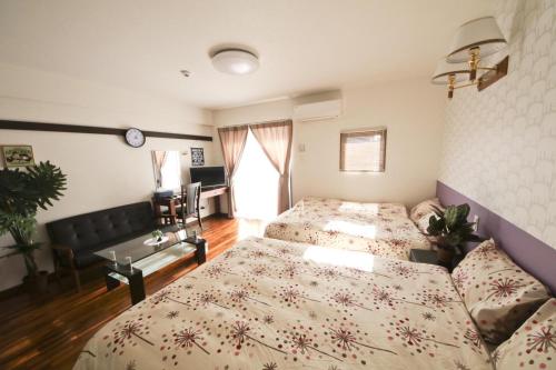 a bedroom with two beds and a couch at Chura Gahna House Tsubogawa Naha in Naha