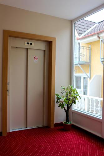 a hallway with a door and a plant next to a window at Lídia Hotel in Harkány