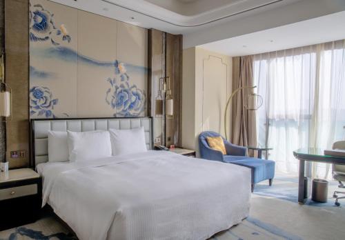a bedroom with a large white bed and a blue painting at Wanda Vista Kunming in Kunming