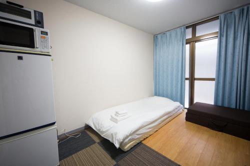 a small room with a bed and a microwave at 102 Uzumasa Arashiyama 2free Bike Wifi in Sagano