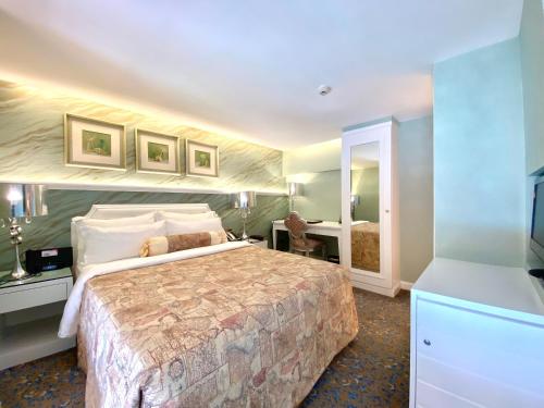 a hotel room with a large bed and a mirror at Hotel Metropole in Macau