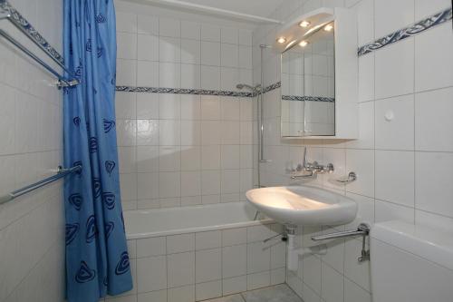 a bathroom with a sink and a tub and a mirror at Apartments Haus Quelle in Leukerbad