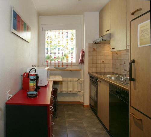 a small kitchen with a red counter and a window at Apartments Haus Quelle in Leukerbad