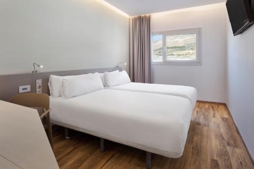 a white bed in a room with a window at B&B HOTEL Almería Vicar in Aguadulce