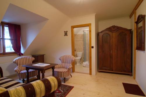 a living room with a table and chairs and a bathroom at Koliba Valaška in Trojanovice