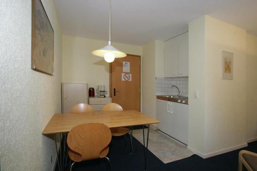 a kitchen with a wooden table and two chairs at Apartments Haus Quelle in Leukerbad
