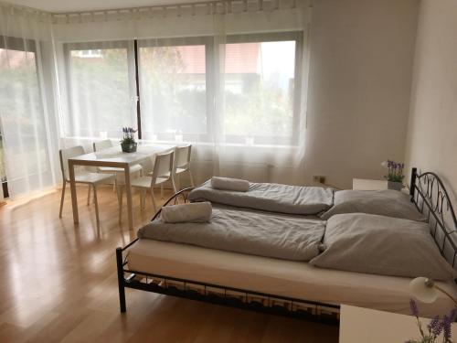 Duas camas num quarto com uma mesa e janelas em Gästehaus Steinmann Apartment 2 Zimmer em Miltenberg
