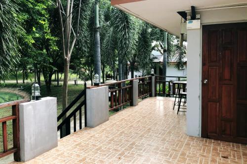 a porch of a house with a wooden door at Resort Railumpoo (Farm and Camping) in Nakhon Sawan