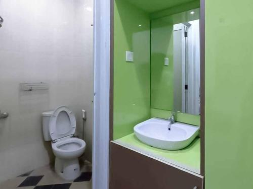 La salle de bains verte est pourvue de toilettes et d'un lavabo. dans l'établissement Aimer Guest House Syariah Mitra RedDoorz, à Cilegon