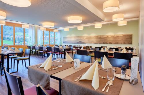 un comedor con mesas, sillas y ventanas en Ferien- und Familienhotel Alpina Adelboden, en Adelboden