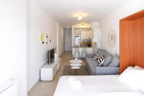 a room with a bed and a couch and a kitchen at Estudio en primera línea Las Canteras in Las Palmas de Gran Canaria