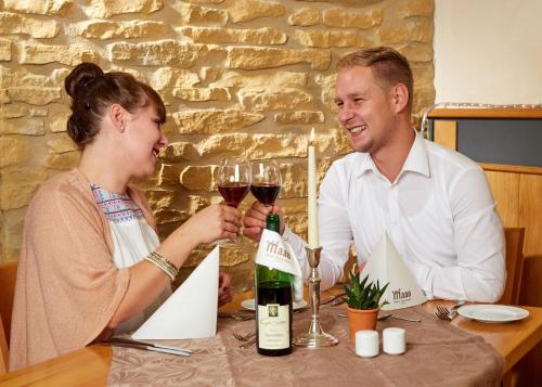 a man and a woman sitting at a table with wine glasses at Hotel-Restaurant Maas in Lutzerath