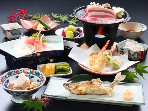 a table topped with different types of food on plates at Maruka Ryokan in Yamanouchi