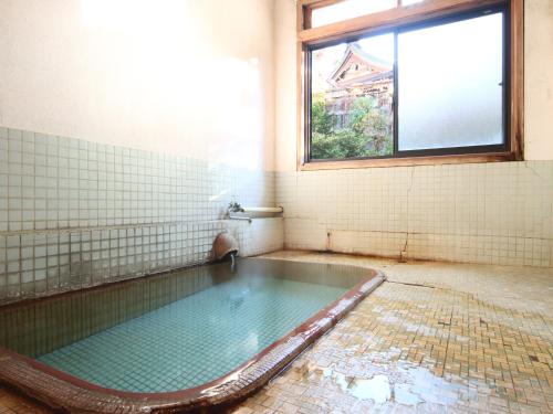 a bathroom with a swimming pool with a window at Maruka Ryokan in Yamanouchi