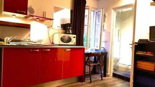 パリにあるスタジオ ル レセペードのキッチン(赤いキャビネット、電子レンジ付)