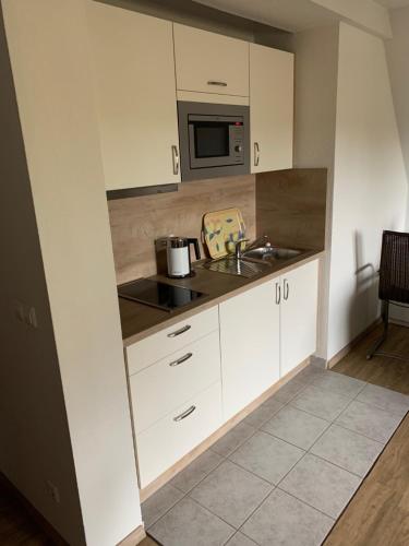 a kitchen with white cabinets and a sink and a microwave at Mare Balticum Urlaub auf Rügen in Sagard
