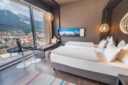 Cette chambre comprend deux lits et une grande fenêtre. dans l'établissement aDLERS Hotel Innsbruck, à Innsbruck