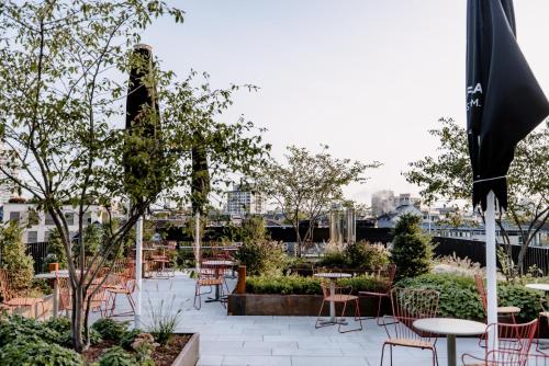 a patio with tables and chairs and trees at THE FLAG West M. in Frankfurt/Main