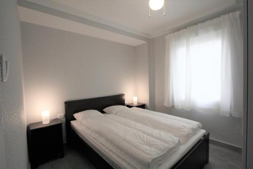 1 dormitorio con 1 cama con 2 mesitas de noche y una ventana en 036 - Sierramar 001 - comfortHOLIDAYS, en Santa Pola
