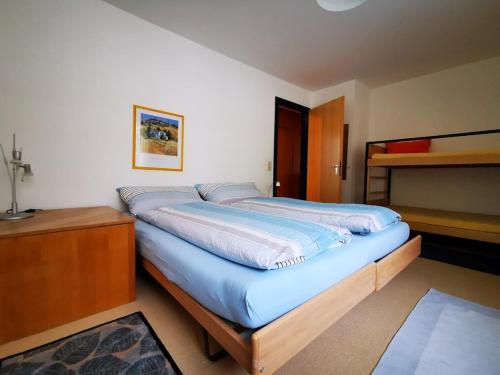 a bedroom with a large bed with blue sheets at Apartments Haus Quelle in Leukerbad