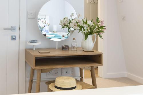 a table with a vase of flowers and a mirror at Fowey Penthouse, Fowey in Fowey