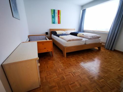 a bedroom with two beds and a table and a window at Apartments Haus Quelle in Leukerbad