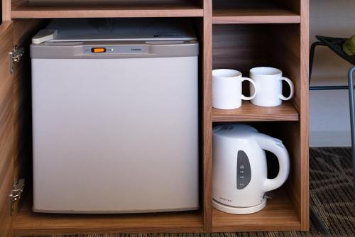 a refrigerator in a cabinet with cups and mugs at The OneFive Fukuoka Tenjin in Fukuoka