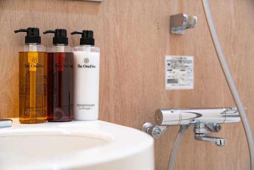 two bottles ofodorizers sitting on top of a sink at The OneFive Fukuoka Tenjin in Fukuoka