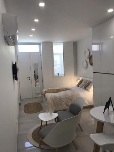 a white bedroom with a bed and a chair at Viana é CORAÇÃO DE OURO in Viana do Castelo
