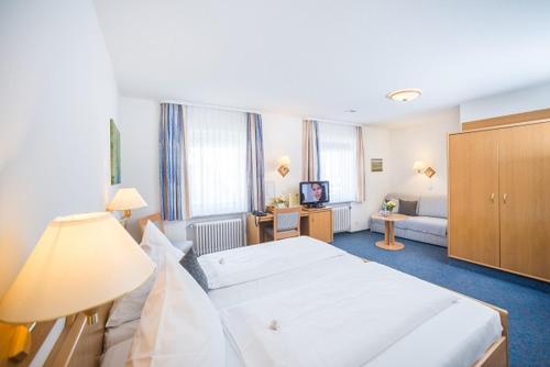 a hotel room with a large bed and a couch at TIPTOP Hotel Garni Pfauen in Endingen