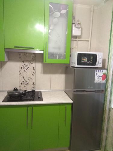 una pequeña cocina con armarios verdes y nevera. en Хорошая однокомнатная квартира в центре города, en Shostka