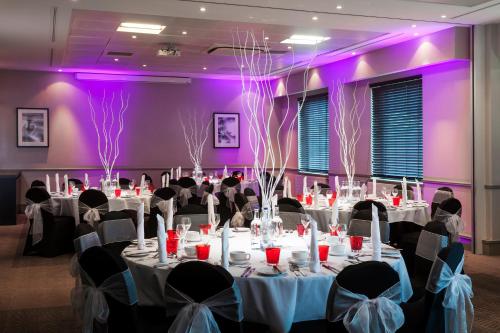 a room with tables and chairs with purple lighting at Crowne Plaza Birmingham NEC by IHG in Bickenhill