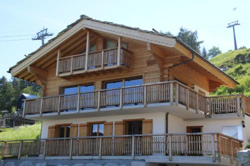 Adele SKI IN & SKI OUT chalet 10 pers في فييسوناز: منزل خشبي مع شرفات على جبل