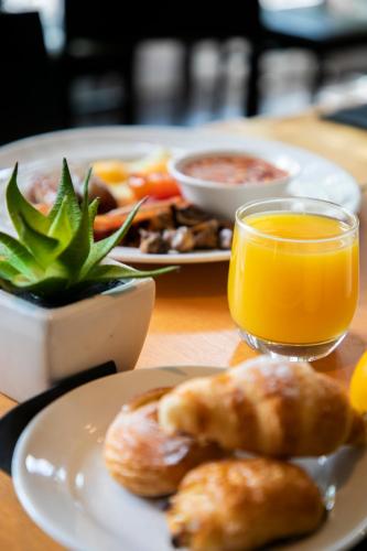 a table with two plates of food and orange juice at Crowne Plaza Birmingham NEC by IHG in Bickenhill