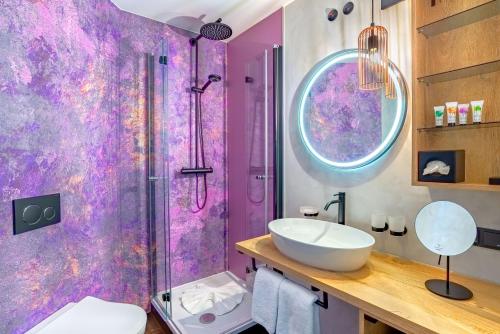 ein lila Badezimmer mit einem Waschbecken und einer Dusche in der Unterkunft Hotel Bei Gretel, Wellness & Ayurveda in Struppen-Siedlung