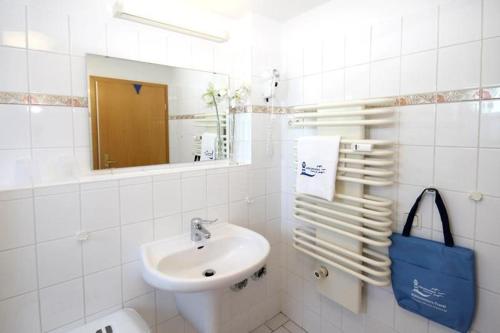 ein weißes Badezimmer mit einem Waschbecken und einem Spiegel in der Unterkunft Residenz Ostseewind - Wohnung 12 / 9571 in Kühlungsborn