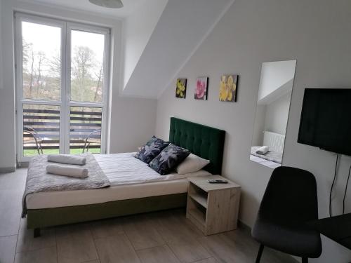 a bedroom with a bed and a tv and a chair at Pan Tadeusz in Zwierzyniec