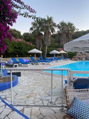 une piscine dans un complexe avec des chaises bleues et des arbres dans l'établissement Residence Fium Del Cavo, à Sainte-Lucie de Porto-Vecchio
